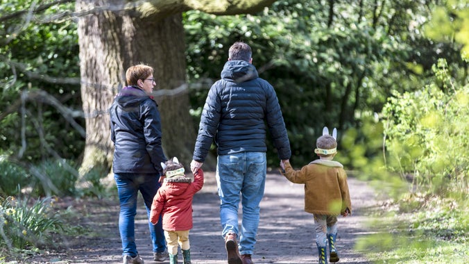 A family holding hands as they walk away from the camera on an Easter trail